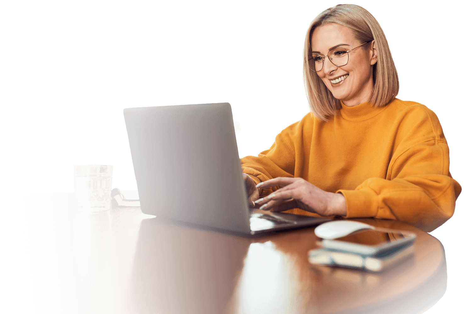 Junge Frau in orangefarbenem Pullover und Brille arbeitet am Laptop und lächelt zum Bildschirm